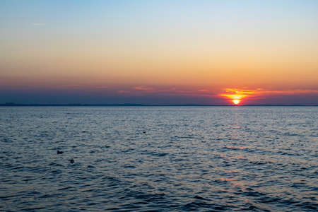 the setting sun against the backdrop of a calm seaの写真素材