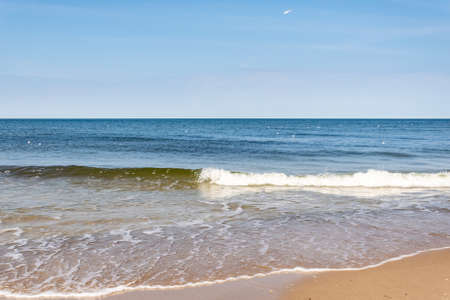 sea waves against the background of yellow sand and blue skyの写真素材