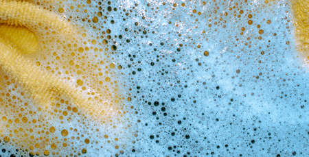 yellow cloth dipped in water with blue foamの写真素材
