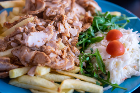 kebab with potato fries and salad on a blue plateの写真素材