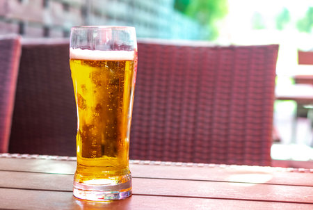 beer in a glass on a brown table with a blurry backgroundの写真素材