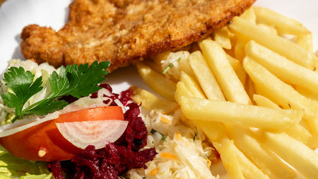 pork chop, fries and salad on a white plateの写真素材