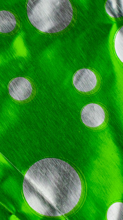 crumpled aluminum foil painted green with silver circles.の写真素材