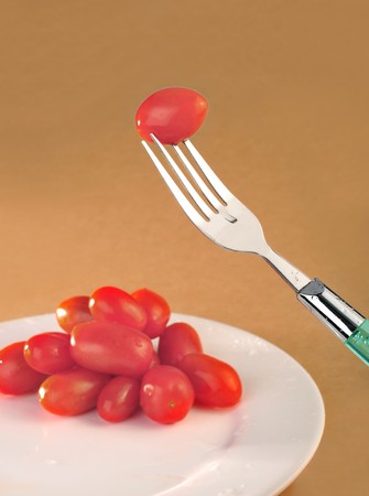 Orange background, small tomatoes and forkの写真素材