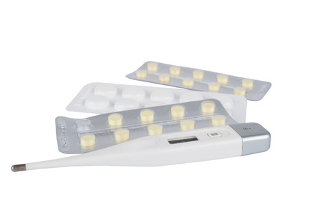 Medical thermometer and pills on a white background
