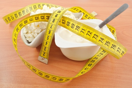 cottage cheese and yogurt with a centimeter tape on a wooden tableの写真素材