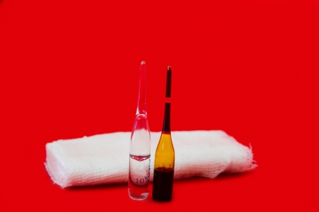bandage and ampoules on a red backgroundの写真素材