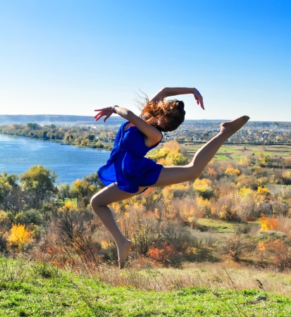 Girl jumping on a background of autumn landscapeの写真素材