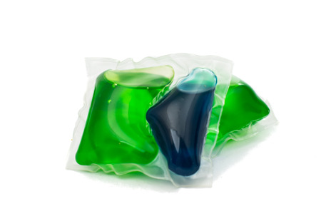 Gel capsules with laundry detergent on a white background.