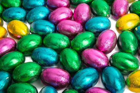 Easter chocolate eggs in foil on white background