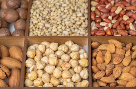 Mixed nut background: pine nuts, pistachios, cashews, almonds, hazelnuts, peanuts, macadamia,...