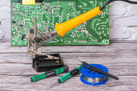 A close-up of an electrical circuit board with a soldering iron and screwdrivers