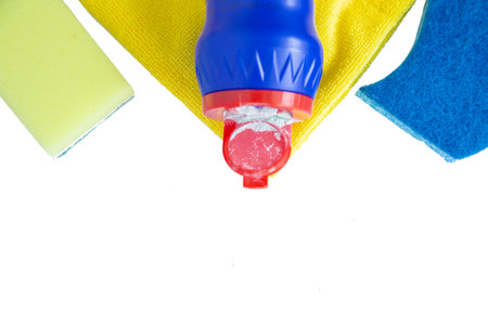 The cleaning agent lies on a yellow terry cloth, flanked by sponges for cleaning surfaces on a white background.の写真素材