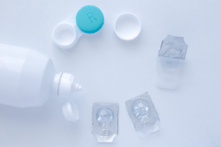 Lens remover, a container for storing lenses and two contact lenses lie on the sides on a white background, there is a place for text. top view, flat lay, copy space, isolateの写真素材