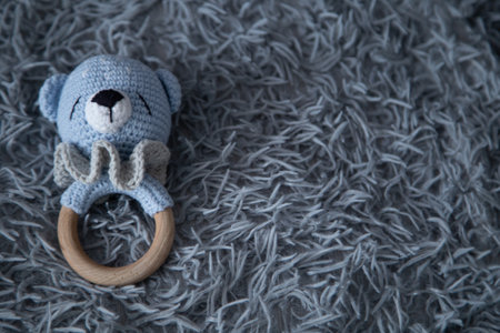 A toy for a baby in the form of a knitted bear cub lies on a fluffy gray background.の写真素材
