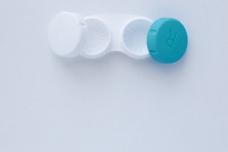 The open container for storing lenses lies on top on a white background with a place for text.top view, flat lay, copy space, isolate. High quality photoの写真素材