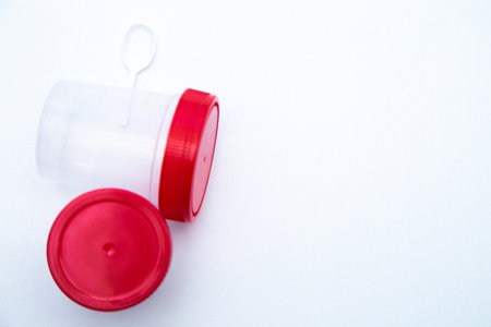 Jars for collecting tests with a red lid and a spoon on a white background. . High quality photoの写真素材