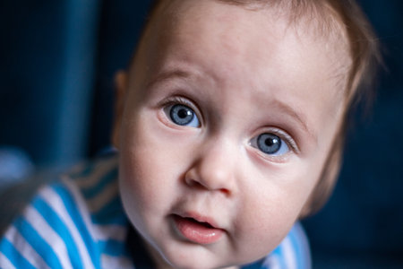 A kid with big blue eyes looks at the camera in surprise, a close-up of his face. High quality photoの写真素材