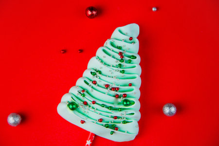 A turquoise bizet Christmas tree on the shelves lies sideways, strewn with colorful powder balls on a bright red background, next to it are red and silver balls. High quality photoの写真素材