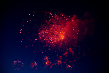 One big red firework with a bright red center hanging against the background of the night sky,...
