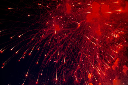 A bright firework with a red glowing center with red sparks and smoke flying towards the background of the night sky. High quality photoの写真素材
