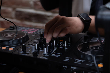 A DJ in a nightclub at the control panel adjusts the music. Music is playing, creating an...