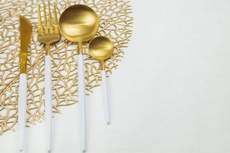 Cutlery knife, fork, spoon and teaspoon with gold color with white handle lie on a napkin of gold color on a white background. The concept of food, culture, and eating. High quality photoの写真素材