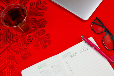 Close-up view from above on a red background there is a pink notebook diary in which it is written:...