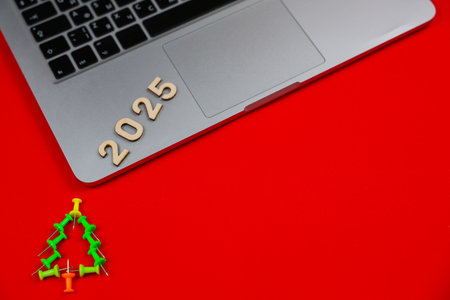 A creative Christmas tree consisting of green stationery pushpins stands on a red background, above...