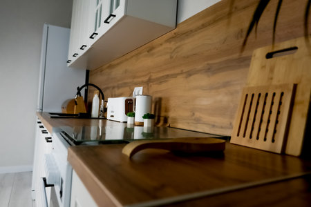 View of the wooden countertop in a modern kitchen in white and wood tones, on which there are wooden...