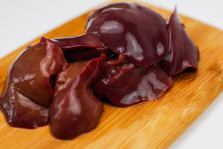 Close-up of raw chicken liver on a wooden board on a white background. The concept of healthy...