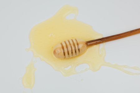 A wooden spoon lies in liquid yellow honey on a white background. The concept of wholesome and healthy food, sweets, natural products. High quality photoの写真素材