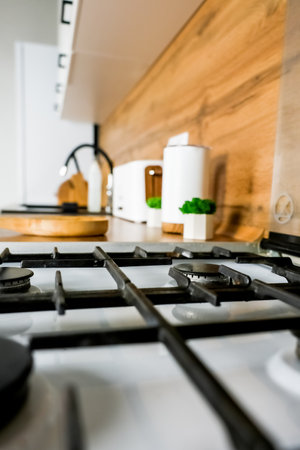 Close-up of a white gas stove with a black cast-iron grate and black burners against the background...