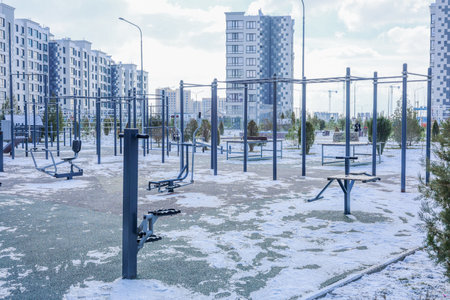 An outdoor sports ground with exercise equipment and horizontal bars against the background of a residential complex of houses of modern architecture in white with gray inserts. The concept of sports, sports grounds, internal amenities of residential complexes. High quality photoの写真素材