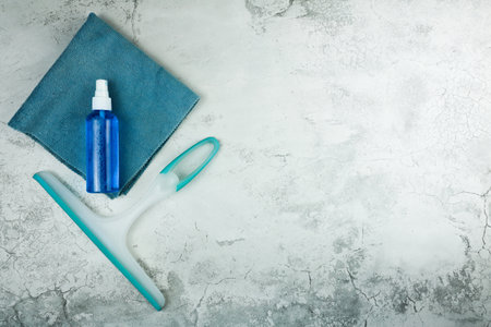 A sleek and efficient cleaning setup includes a spray bottle, a cloth, and a squeegee on a modern...