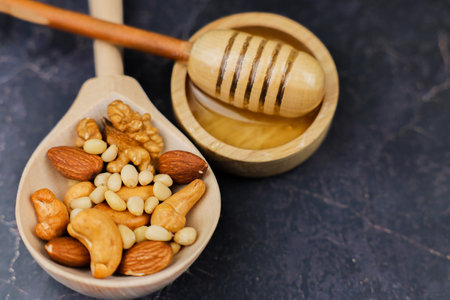 A crafted wooden spoon filled with a delightful mix of nuts and honey, perfect for snacks and recipesの写真素材