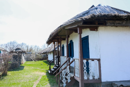 A picturesque view of a charming cottage with a thatched roof, surrounded by vibrant, lush greeneryの写真素材