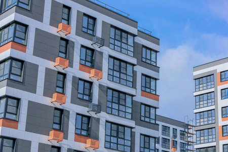 Contemporary apartment complex featuring sleek architecture and air conditioning, set against a clear blue sky.の写真素材