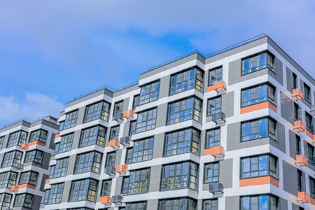 A stunning architectural view showcasing a modern multifamily apartment building set against a clear blue skyの写真素材