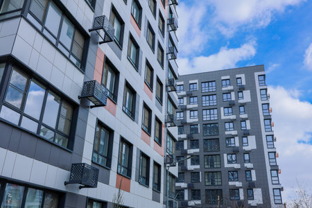 Contemporary residential architecture characterized by prominent balconies and expansive windows on a bright sunny dayの写真素材