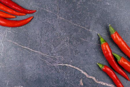 Vibrant red chilies are artfully arranged on a sleek dark marble background, ideal for culinary inspirationの写真素材