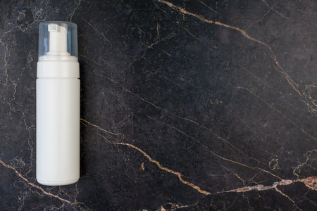 A stylish foam pump bottle is showcased beautifully against a luxurious, dark marble background, enhancing its appealの写真素材