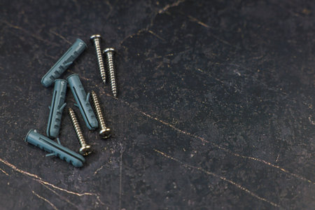 A variety of screws and anchors is meticulously arranged on a dark, textured surface to showcase themの写真素材