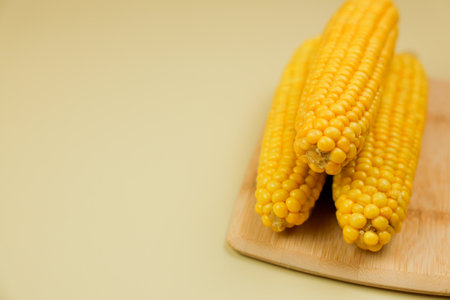 Side view of yellow ripe peeled corn cobs with large grains lying on wooden board on side on yellow background with space for text. The concept of healthy nutrition, natural iron, corn cultivation. High quality photoの写真素材