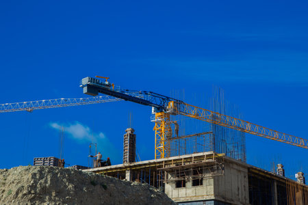 A large yellow crane at the construction site lifts materials over a partially constructed structure...