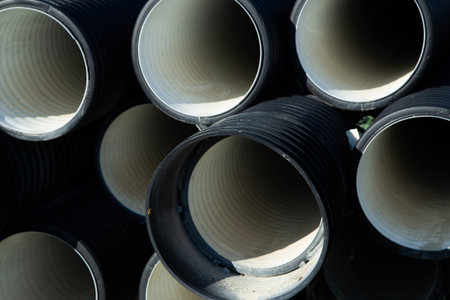 The black drainage pipes are neatly stacked, showcasing smooth interior surfaces and industrial...