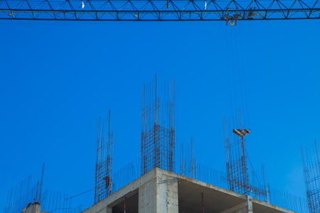 A construction site with a crane lifting materials over a building under construction, surrounded by...