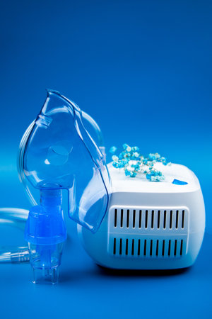 Close-up side view of a blue mask and a device on a blue background and flowers nearby. The concept...