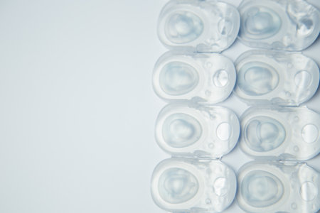 Several rows of daily contact lenses in a disposable protective case lie on the side on a white background with space for text. The concept of ophthalmology, vision correction, eye care. High quality photoの写真素材
