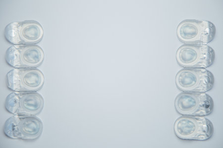 Daily disposable contact lenses in a disposable protective case lie in rows on the sides on a white background with space for text in the center. The concept of ophthalmology, vision correction, eye care. High quality photoの写真素材